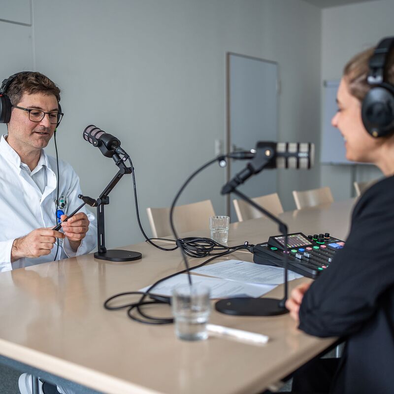 Arzt im Podcaststudio, er hält einen Reflexhammer in der Hand.