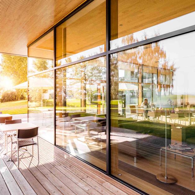 Draußen auf der Terrasse stehen zwei Tische mit Stühlen.